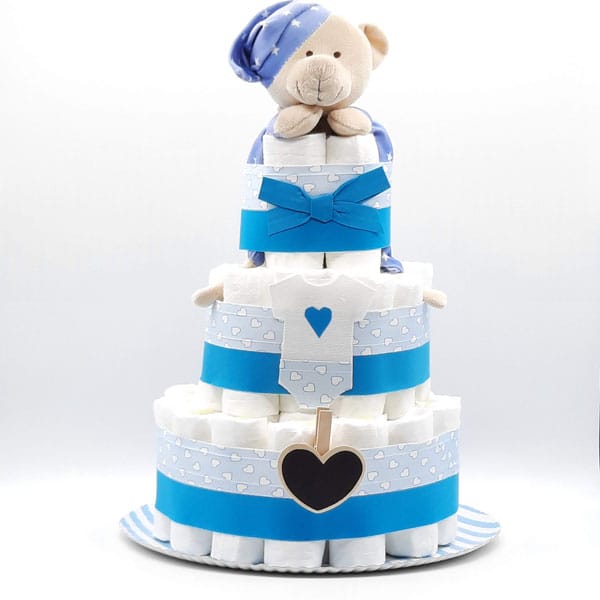 Tarta de pañales azul con osito con gorro de dormir, corazones y pizarrita de corazón