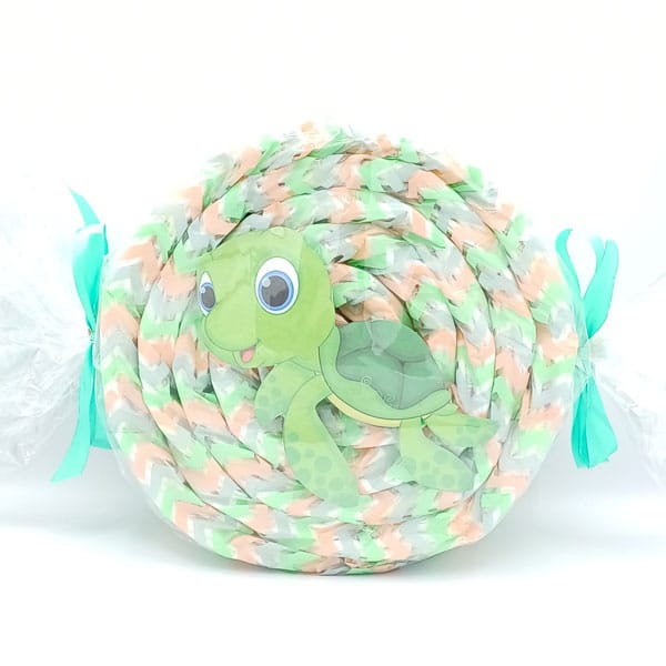 Caramelo de pañales con tortuga verde y envoltorio en tonos verde y melocotón